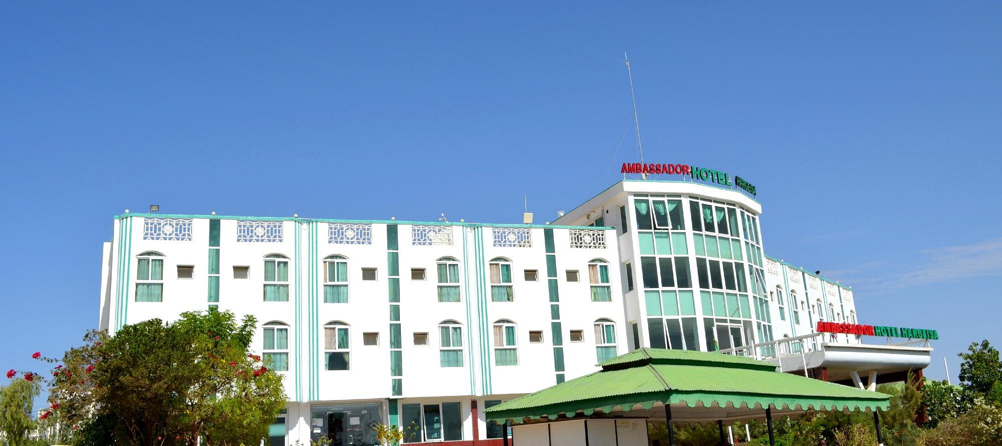 Ambassador Hotel Hargeisa's white and green building under a clear blue sky, with its rooftop sign