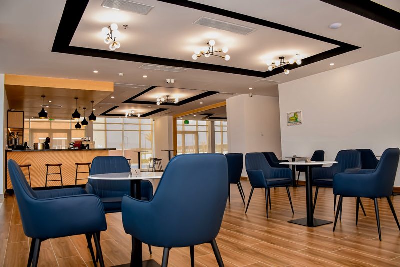 Café tables with blue armchairs and the coffee bar behind