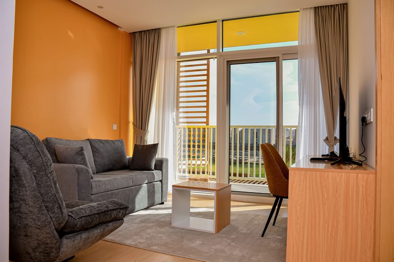 An en-suite room living area with a sofa, desk and doors onto a private balcony
