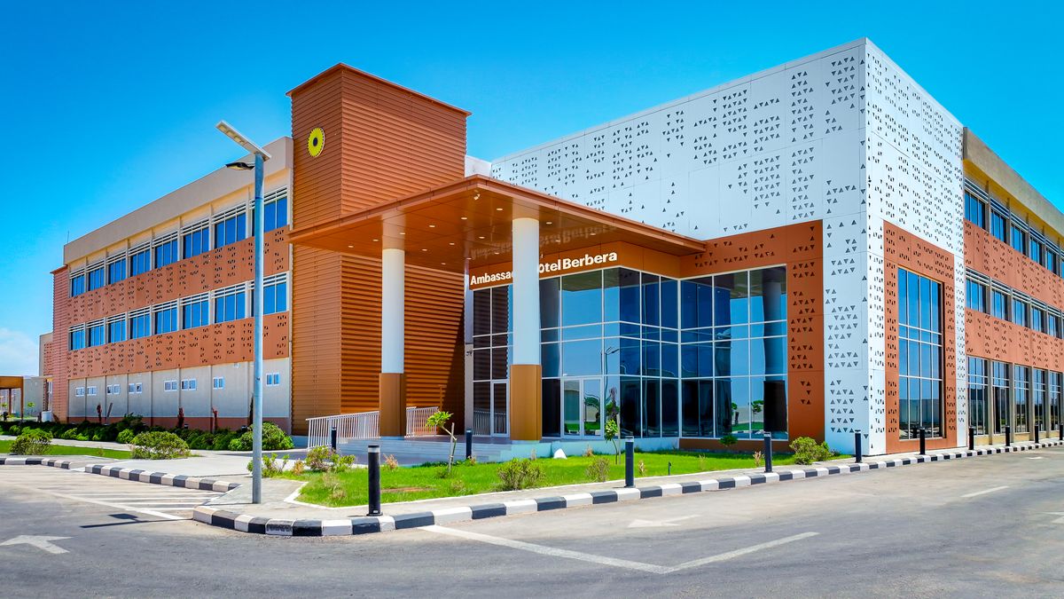 The main hotel building with its glass entrance and terracotta and white facade