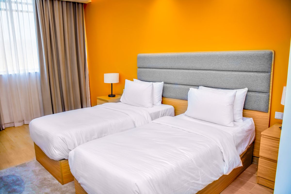 A Deluxe Room set up as a twin, with two made-up single beds and a grey headboard