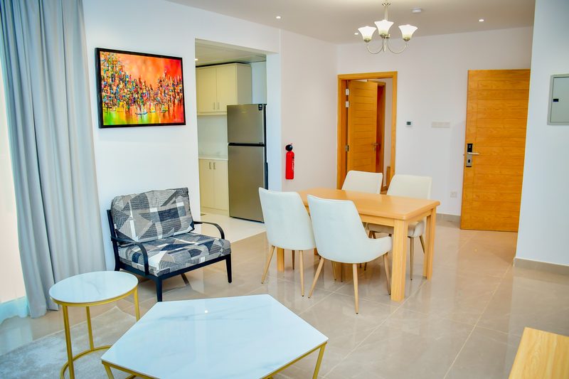 Villa living and dining area, with an armchair, a dining table and the kitchen beyond