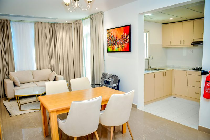 Villa living area with a sofa, a dining table for four and the kitchen