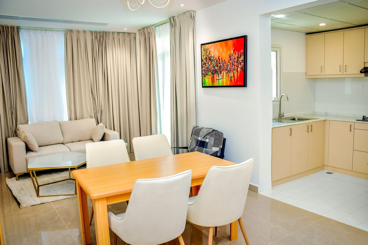 A villa living area with a sofa, a dining table and an open kitchen