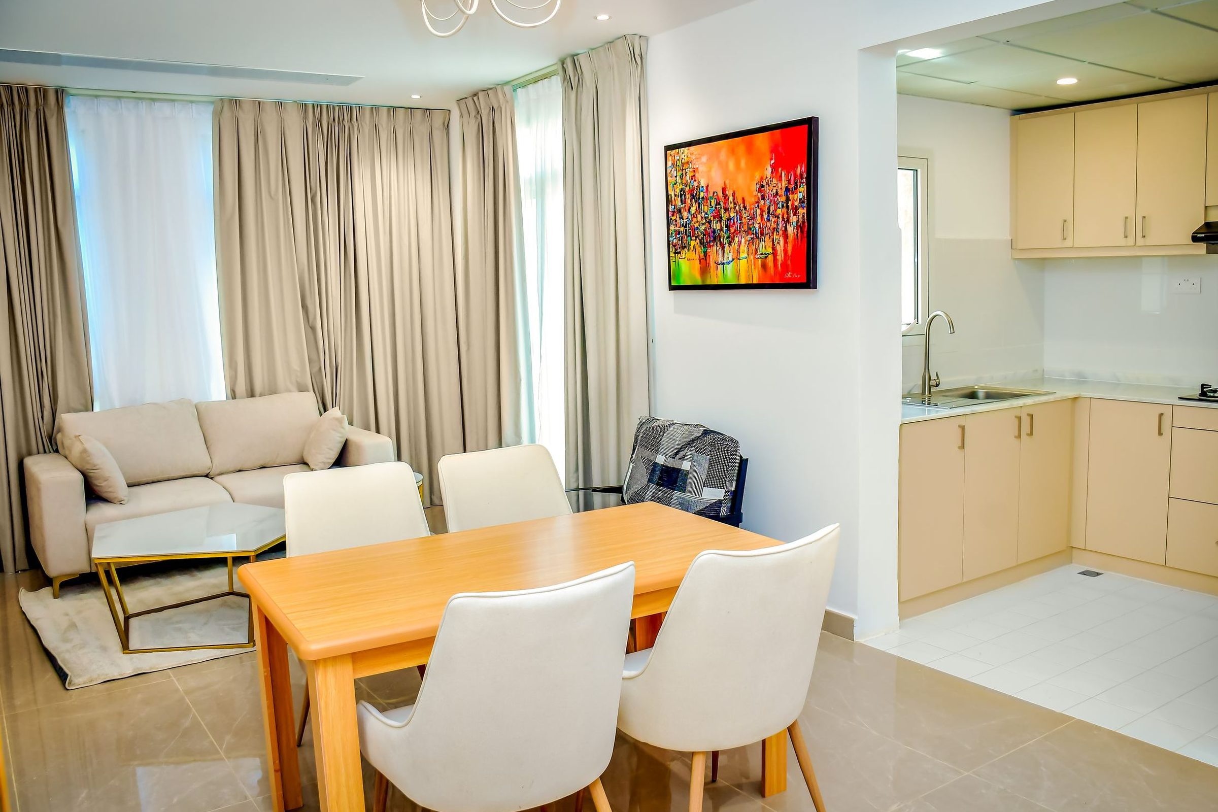A villa living area with a sofa, a dining table for four and an open kitchen